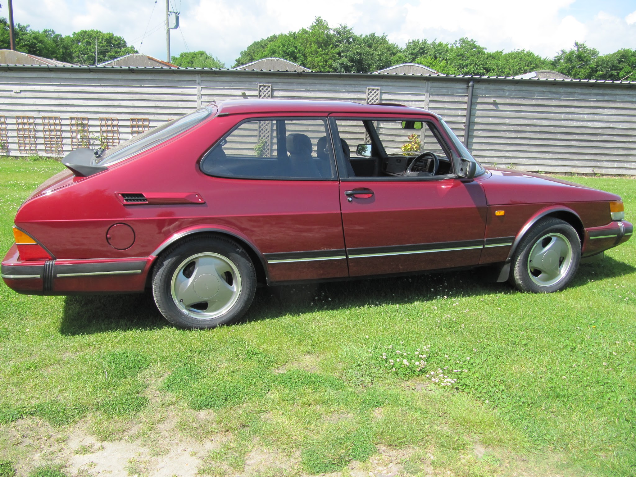 A burgundy classic SAAB 900 three-door outside the Woods Corner workshop